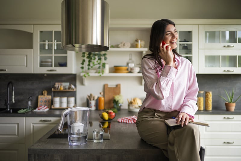donna-seduta-in-cucina-con-caraffa-laica-healthexpert