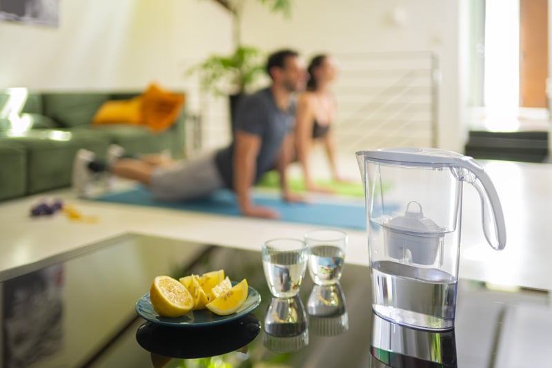 uomo-e-donna-fanno-yoga-in-primo-piano-caraffa-con-alkawater
